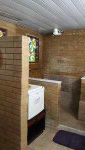 a bathroom with a brick wall and a white appliance at Hotel Fazenda Terra Ramos in Papucaia