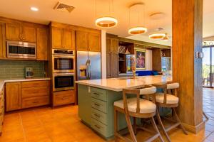 eine Küche mit Holzschränken und eine Insel mit Barhockern in der Unterkunft Bougainvillea 7315 Luxury Penthouse Adults Only - Reserva Conchal in Playa Conchal