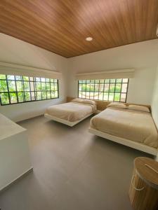 een slaapkamer met 2 bedden en 2 ramen bij Casa Finca Soluna in Cumaral