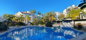 a large swimming pool with palm trees and buildings at Jardines de las Golondrinas Elviria by the Nikki beach in Marbella