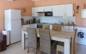 a kitchen with a wooden table with chairs and a refrigerator at Nice Home In Rayol-canadel-sur-mer With 2 Bedrooms, Wifi And Outdoor Swimming Pool in Rayol-Canadel-sur-Mer