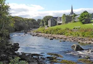 a river with rocks and a church in the background at Haven Pod Easkey in Sligo