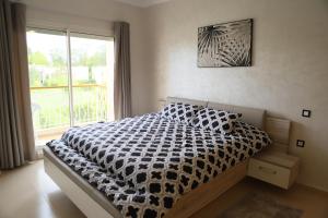 una camera da letto con un letto bianco e nero e una finestra di Golf Royal appartement a Fes