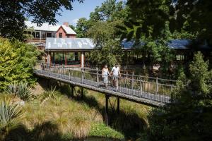 zwei Menschen, die über eine Brücke über einen Fluss gehen in der Unterkunft Millbrook Resort in Arrowtown