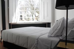 sypialnia z białym łóżkiem i oknem w obiekcie Largo da Sé Guest House - HOrigem w Lizbonie