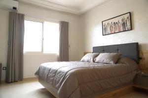 1 dormitorio con 1 cama grande y ventana en Golf Royal appartement en Fez