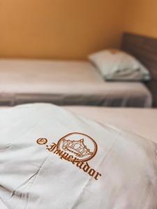 um logótipo num cobertor branco numa cama em Pousada do imperador em Piranhas