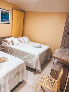 a hotel room with two beds and a chair at Pousada do imperador in Piranhas