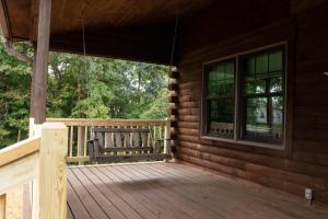 a porch of a log cabin with a bench on it at Maple Leaf Cabin in Millersburg