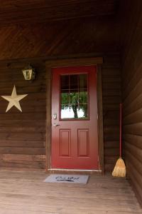 a red door in a wooden house with a star on the wall at Maple Leaf Cabin in Millersburg