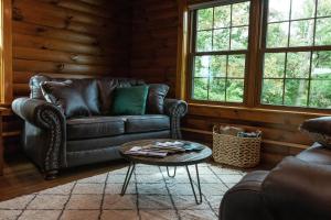 a living room with a leather couch and a table at Maple Leaf Cabin in Millersburg