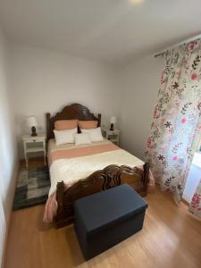 a bedroom with a large bed and a blue ottoman at Casa dos Telhados 