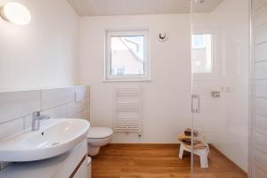 een witte badkamer met een wastafel en een toilet bij Am Thie in Hoisdorf