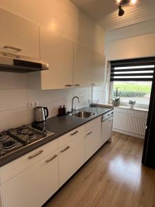 a kitchen with white cabinets and a sink and a window at StayAtSea in Katwijk aan Zee