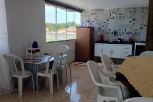 una cucina con sedie bianche, tavolo e tavolo e una cucina con di Mar e Sol de Araruama ad Araruama