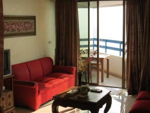a living room with a red couch and a table at Jomtien Plaza Suite Apartments in Jomtien Beach