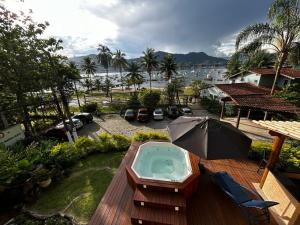 a hot tub on a deck with an umbrella at Casa Amarela in Angra dos Reis