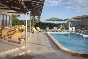 a pool with chairs and umbrellas next to a house at Villa Albena Bay View in Albena