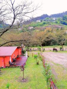 a red house with a deck and a horse in a field at Quinta Do Fijo in Arcos de Valdevez