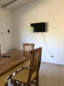 a wooden table with two chairs and a television on a wall at Vista Andes VII in Ciudad Lujan de Cuyo