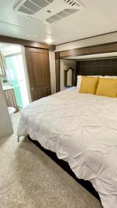 1 dormitorio con 1 cama blanca grande con almohadas amarillas en Beachy Getaway & Small Dog Friendly en Bolivar Peninsula
