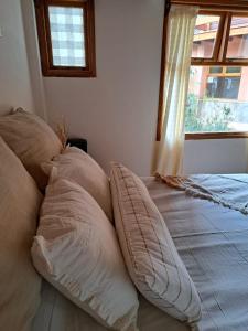 1 cama con almohadas junto a una ventana en Casa Alta 8, en San Martín de los Andes