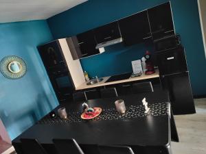 une cuisine avec une table noire et des armoires noires dans l'établissement Charmant logement avec Spa, Sauna et terrasse, à Bergues