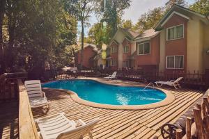 een zwembad op een houten terras met stoelen en een huis bij Hotel y Cabañas Borde Andino in Las Trancas