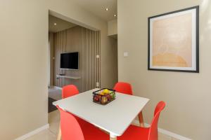 a dining room with a white table and red chairs at Sea Stars Apartment 1 in Perea