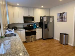 a kitchen with white cabinets and stainless steel appliances at Cottage by the bay, sleeps 8 near Rehoboth beach in Lewes