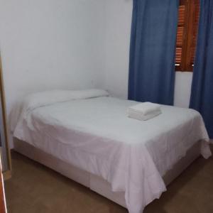 1 dormitorio con 1 cama con sábanas blancas y cortinas azules en CASA FRANCISCO en Córdoba