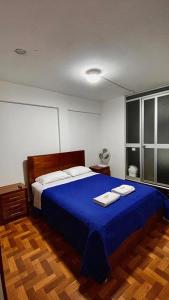 1 dormitorio con 1 cama azul y 2 toallas en Departamento completo Chanchamayo, en La Merced