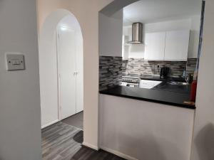 a kitchen with white cabinets and a black counter top at 1 bedroom service apartment with Netflix in West Thurrock