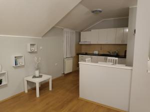 a kitchen with a white counter and a table at Apartman Mima in Borča