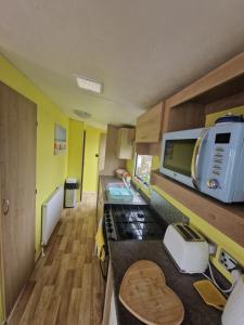 a small kitchen with a stove and a microwave at Lovely caravan at Harts Holiday Park Leysdown-on-Sea in Leysdown-on-Sea