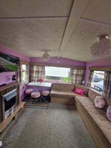 a living room with a couch and a table at Lovely caravan at Harts Holiday Park Leysdown-on-Sea in Leysdown-on-Sea