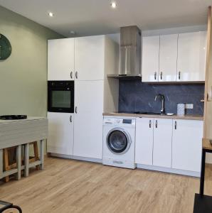 een keuken met witte kasten en een wasmachine bij T2 Cosy proche centre ville avec parking gratuit in Ajaccio