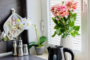 a vase filled with pink and white flowers on a counter at Cozy 1-Bedroom flat in the very Center of Sofia in Sofia
