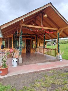 a large wooden pavilion with a deck with potted plants at Glamping El Reencuentro in Machachi