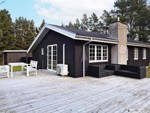 una casa nera con un grande ponte davanti di Holiday home Blåvand VI a Blåvand