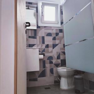 a bathroom with a toilet and a window at Seaside apartment in Agioi Theodoroi