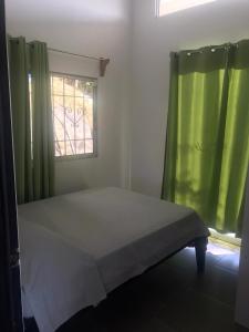 a bedroom with a bed and a window with green curtains at El Poro Puriscal in San José