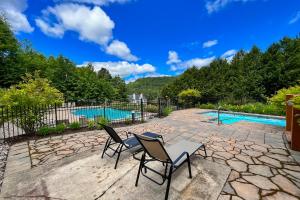 a patio with two chairs and a pool at L'Intemporel by Gestion ELITE in Mont-Tremblant