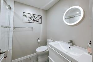 a white bathroom with a sink toilet and a mirror at L'Intemporel by Gestion ELITE in Mont-Tremblant