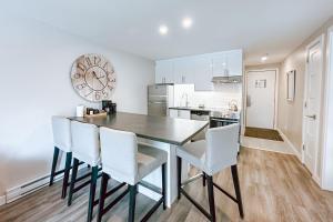 a kitchen with a dining room table and white chairs at L'Intemporel by Gestion ELITE in Mont-Tremblant