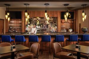 a bar with blue chairs and a man standing behind the bar at Villas at Eldorado Resort in Kelowna