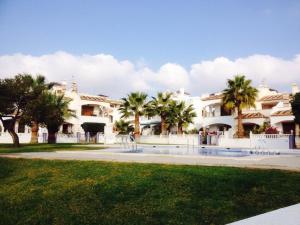Un gran edificio blanco con palmeras delante. en Jumilla III, en Orihuela Costa