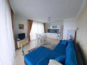 a living room with a blue couch and a kitchen at Private Apartments by the sea with a large terrace in Apart hotel! in Pomorie