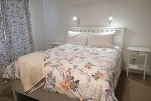 a bedroom with a bed with a floral bedspread at Twodogfolly at Creeklands in Armidale