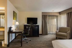 ein Hotelzimmer mit einem Schreibtisch, einem Bett und einem TV in der Unterkunft Best Western Grove City Inn in Grove City